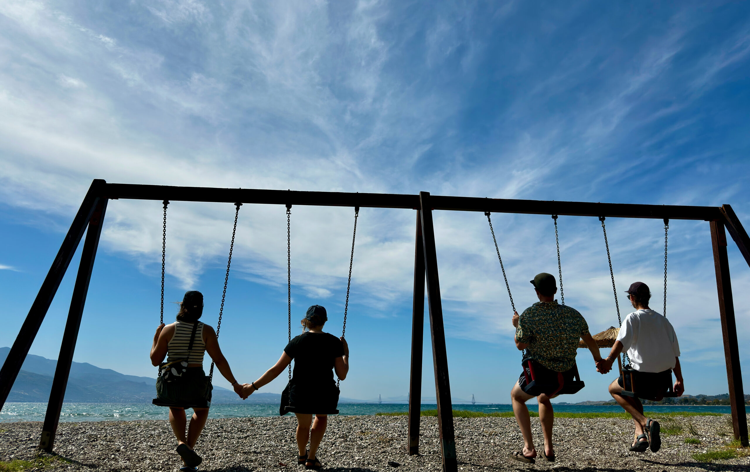 Quatre scout·e·s profitant de la vue sur la mer depuis leurs balançoires.