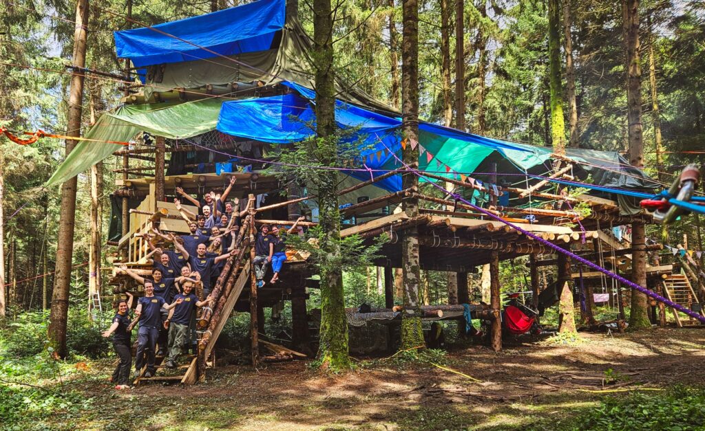 Les participant·e·s du camp posent fièrement devant la cabane terminée.