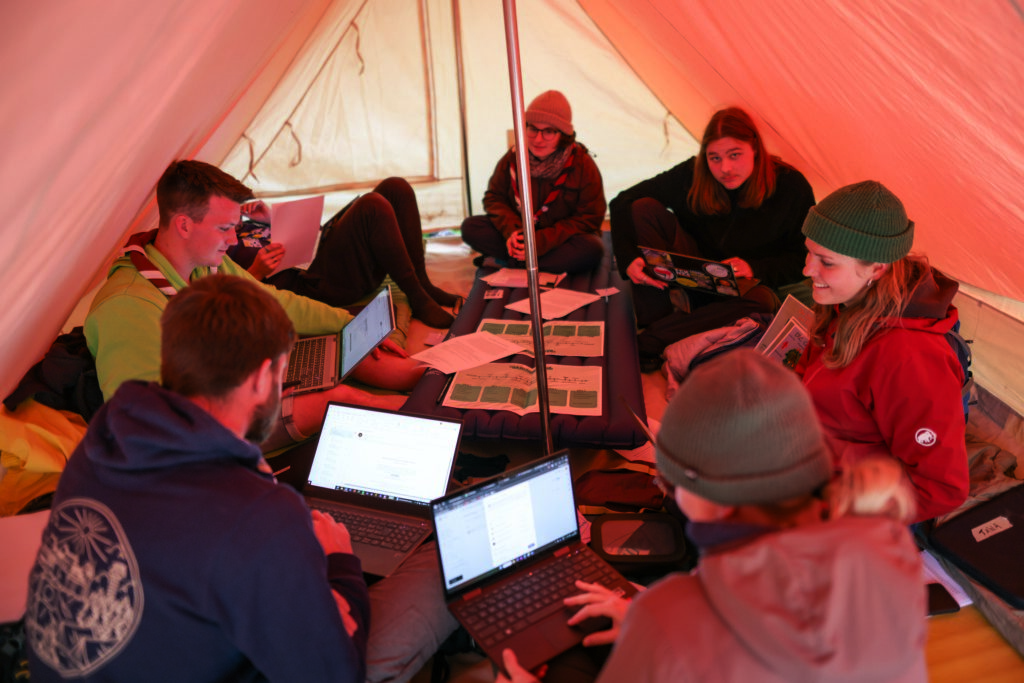 Eine Leitungsgruppe sitzt im Zelt und plant Aktivitäten.